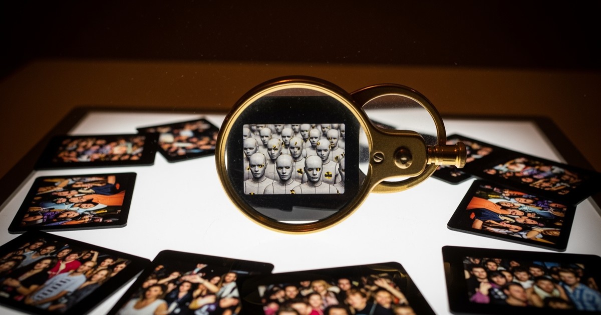 A magnifying loupe on a backlit photography light table reveals that a film slide of a concert crowd is actually composed of rows of